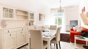 A bright living room with a dining area, a red sofa, a TV, and a chandelier. - Acquadimare (Viareggio)