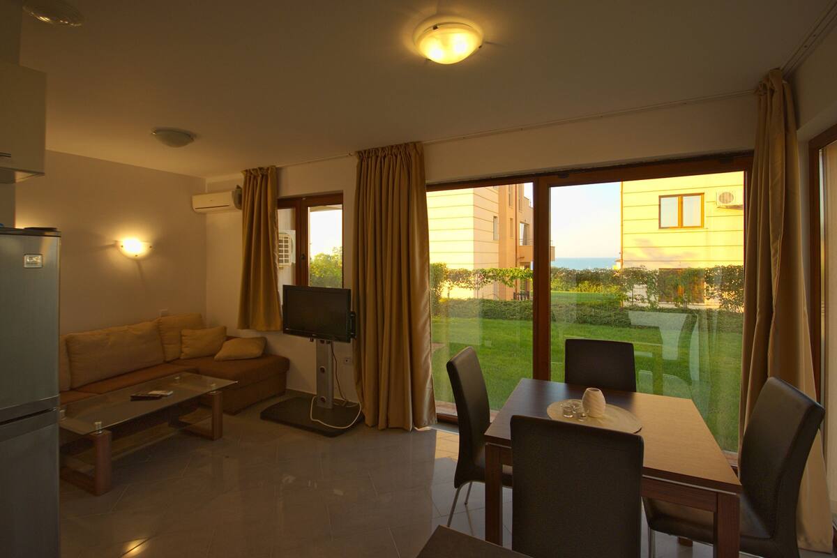 A modern living room with a sofa, coffee table, TV, and dining area with chairs and a table.
