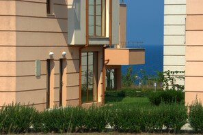 A modern building with a glass door, a balcony, and a view of the sea. - Seagarden Villa Resort (Tsarevo)