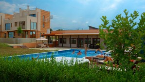 A swimming pool area with a building in the background, surrounded by greenery. - Seagarden Villa Resort (Tsarevo)