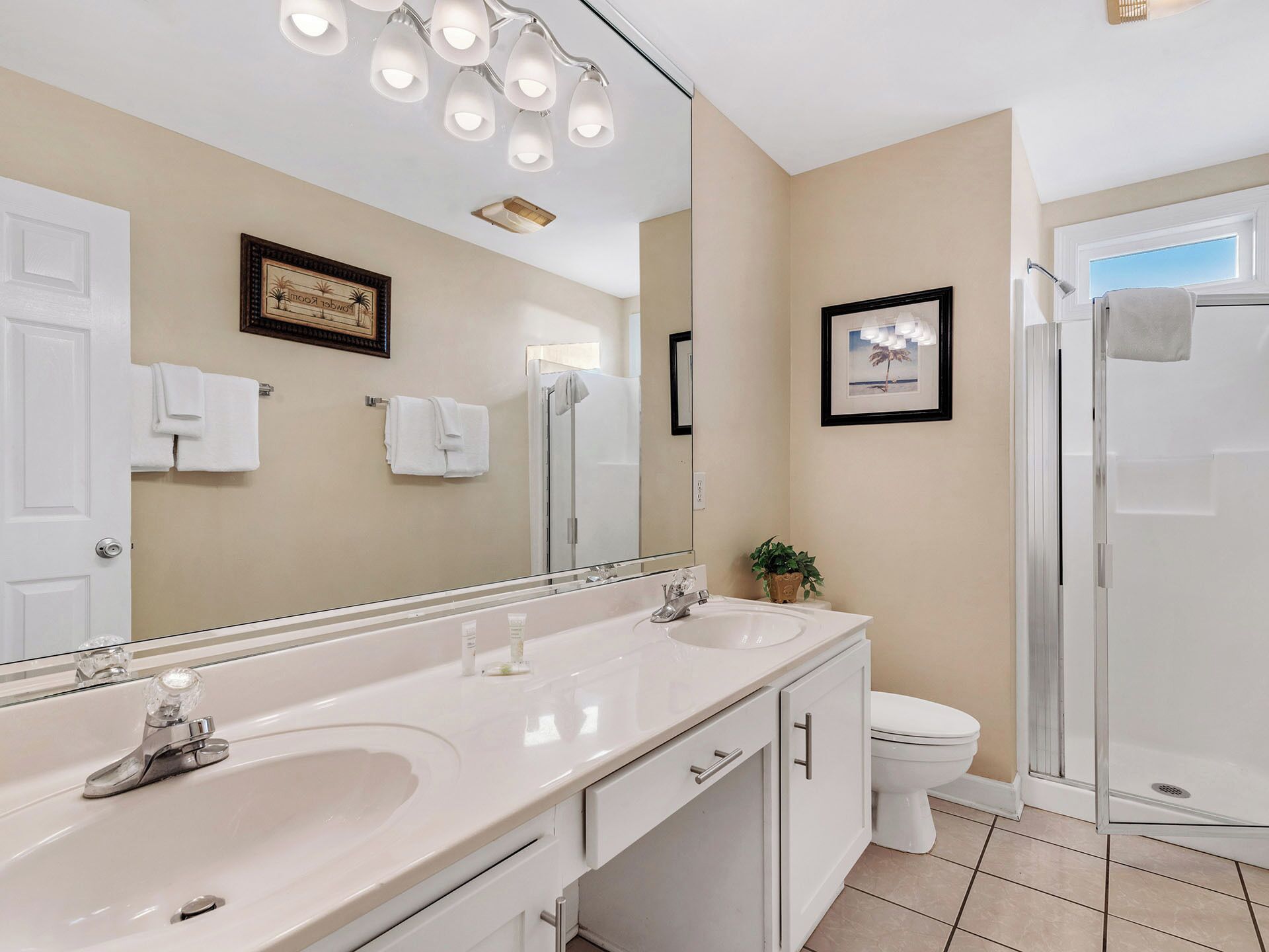 A bathroom with two sinks, a toilet, a shower, and a large mirror.