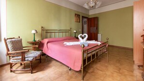 Una habitación con una cama, un sillón mecedora, un aparador de madera y una puerta.