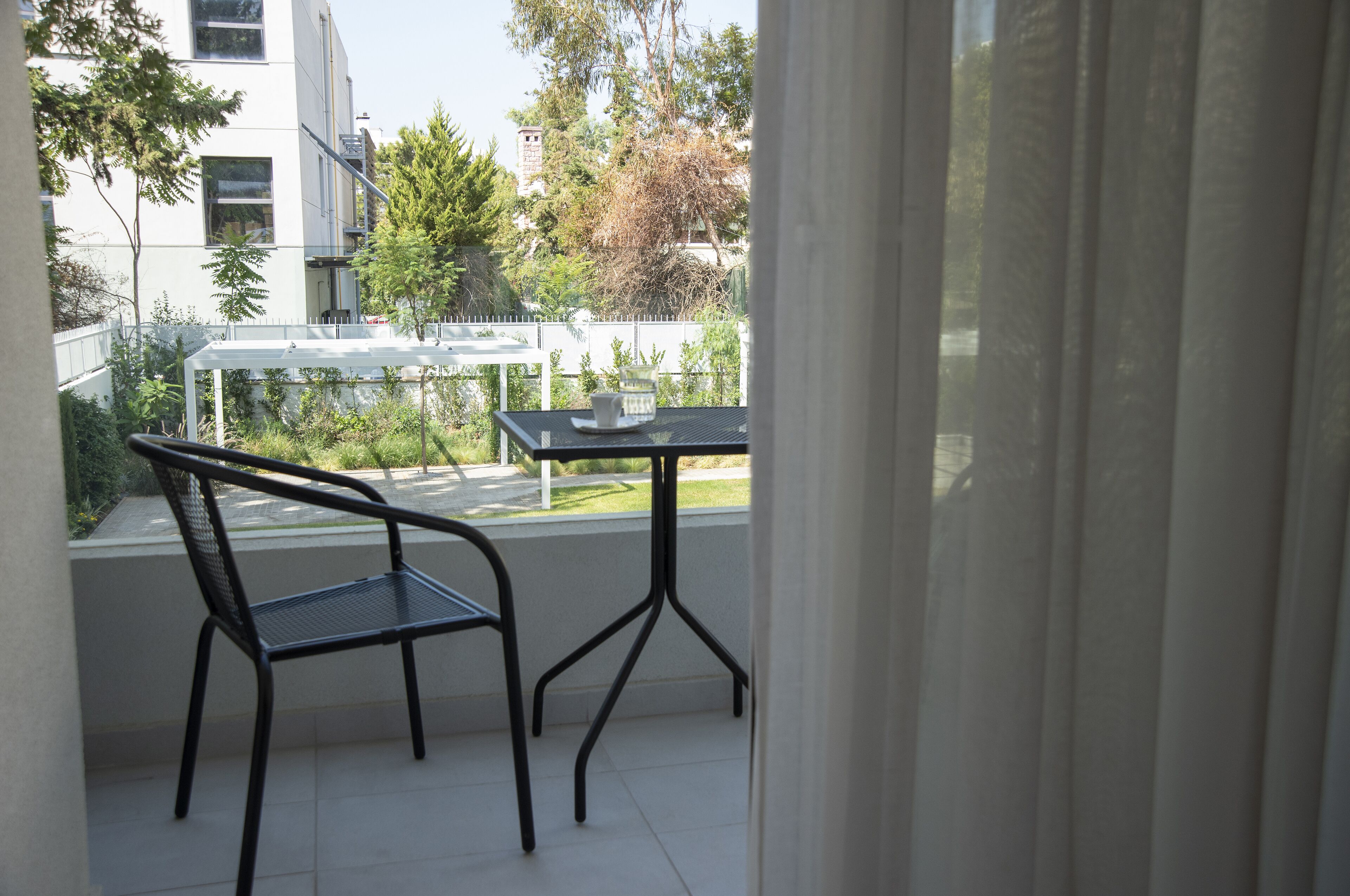Ein Balkon mit Tisch und Stühlen, mit Blick auf einen Garten und Gebäude.