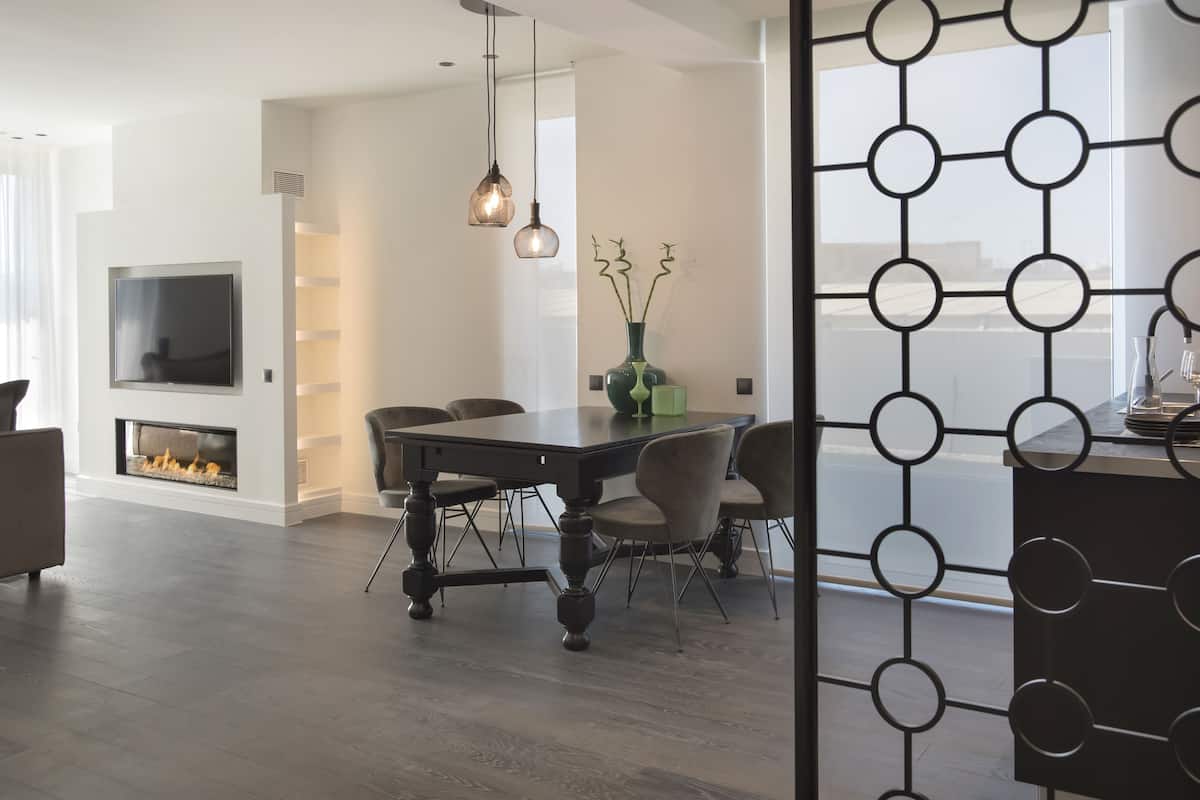 A modern living room with a fireplace, dining table, and chairs.