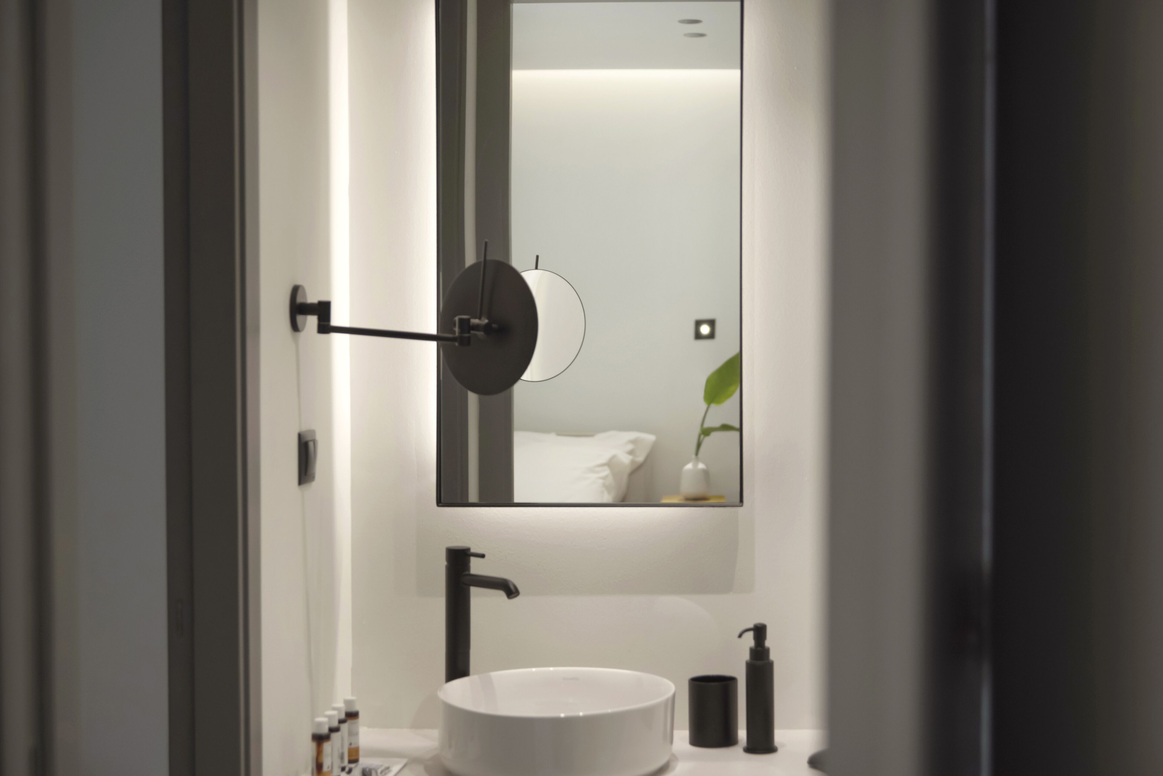 A modern bathroom with a round white sink, a black faucet, a mirror, and a wall-mounted towel rack.