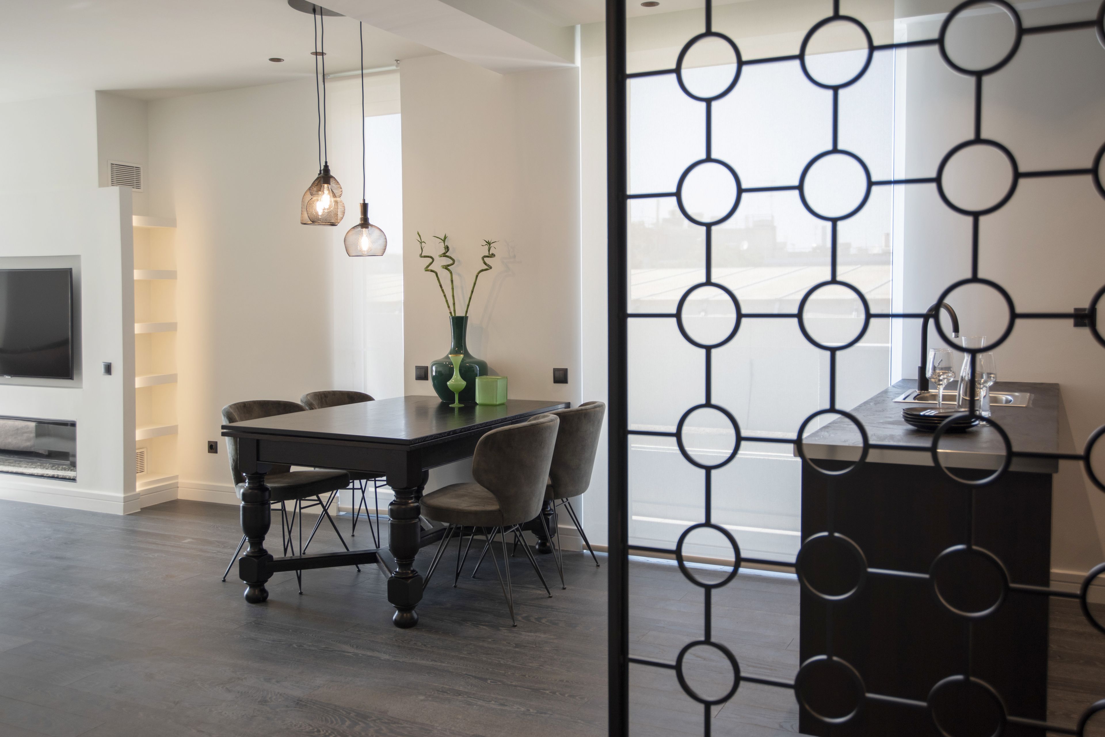Un comedor moderno con una mesa de madera oscura, sillas tapizadas e iluminación colgante.