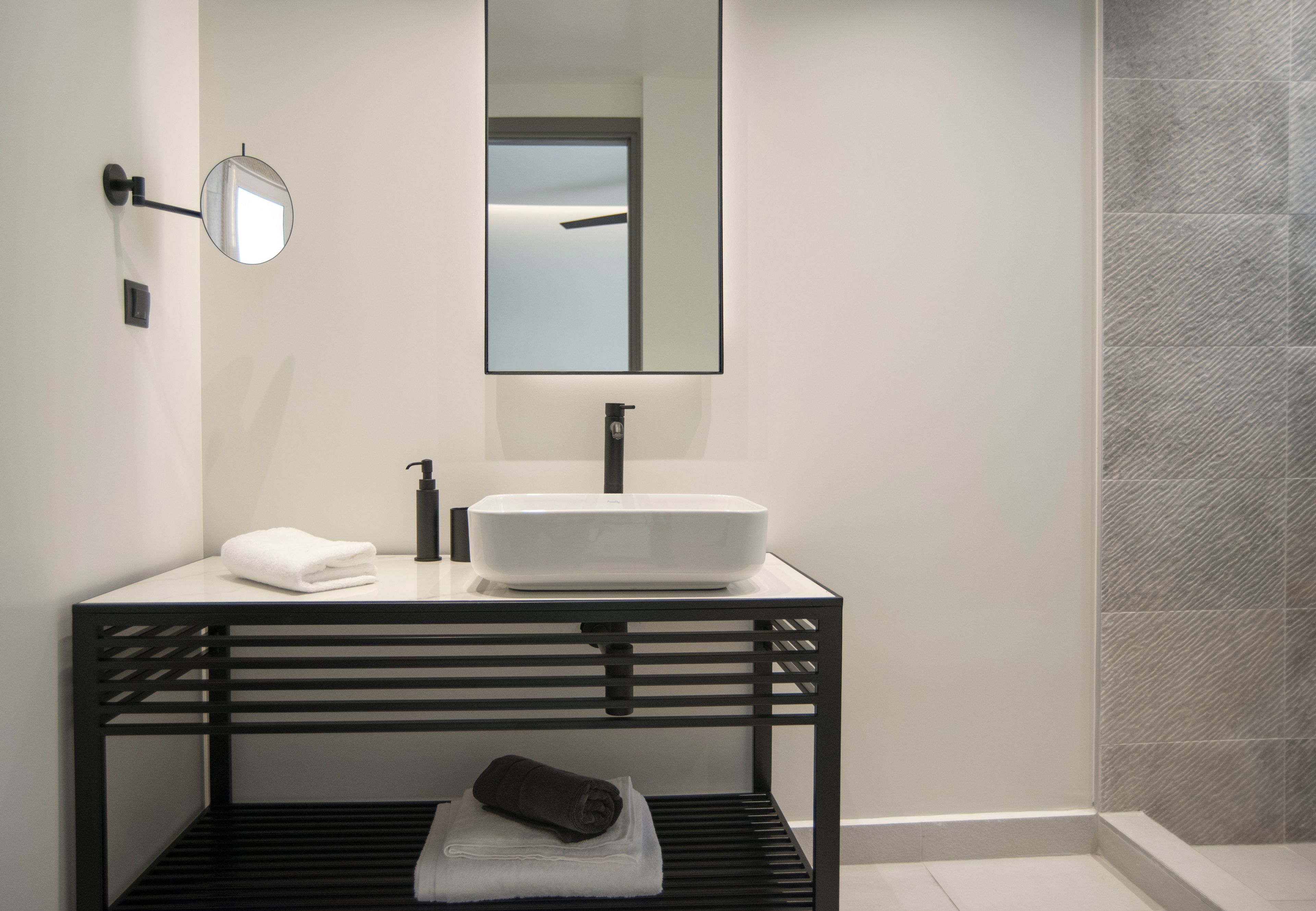 A modern bathroom with a black console table, a white sink, and a mirror.