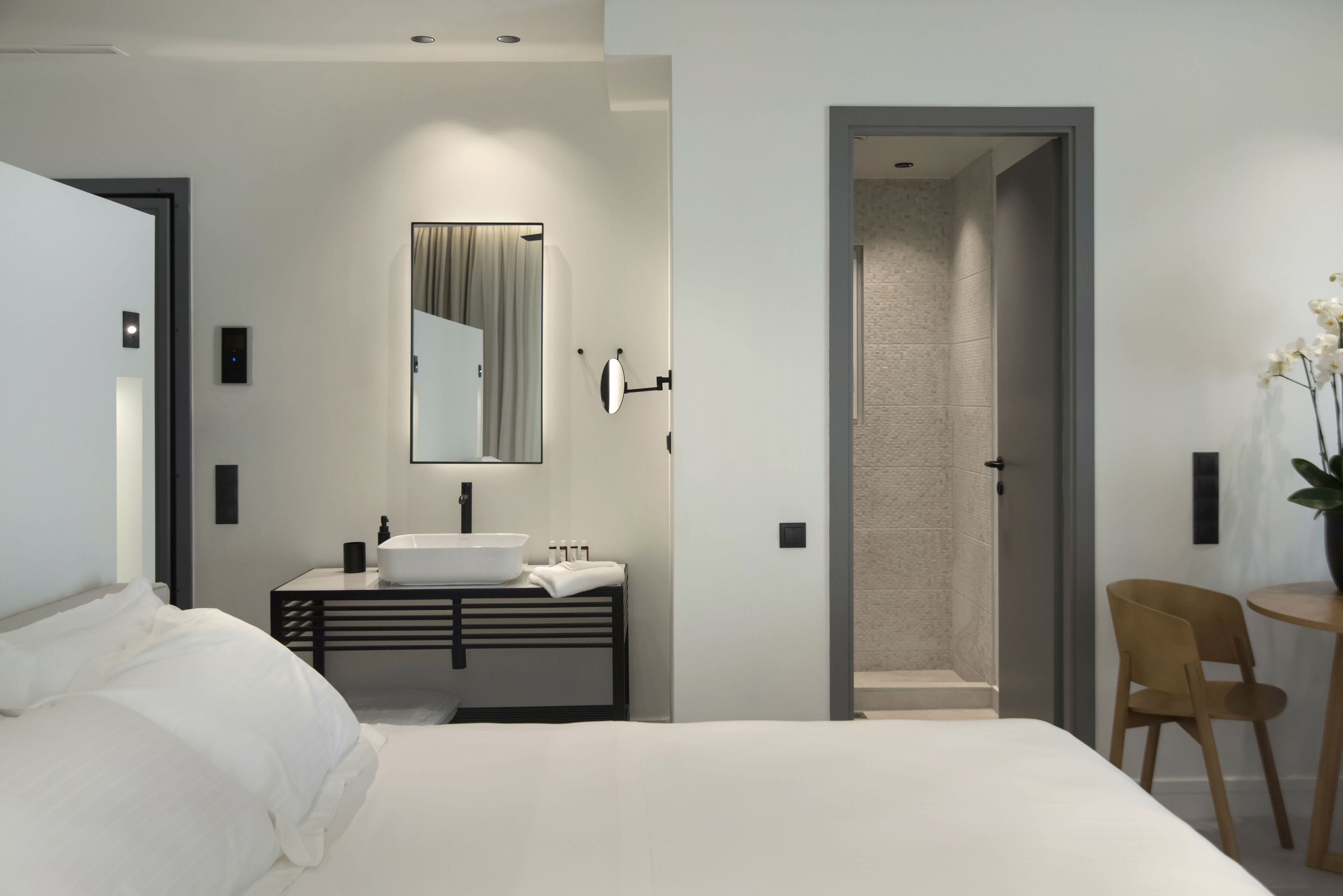 Une chambre moderne avec un grand lit, une table de chevet, un lavabo intégré et un miroir.