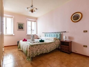 Une chambre à coucher comprenant un lit, une table de chevet, une commode, une fenêtre et un lustre.
