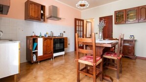 Une cuisine avec des meubles en bois, un plan de travail blanc et un coin repas avec des chaises en bois.