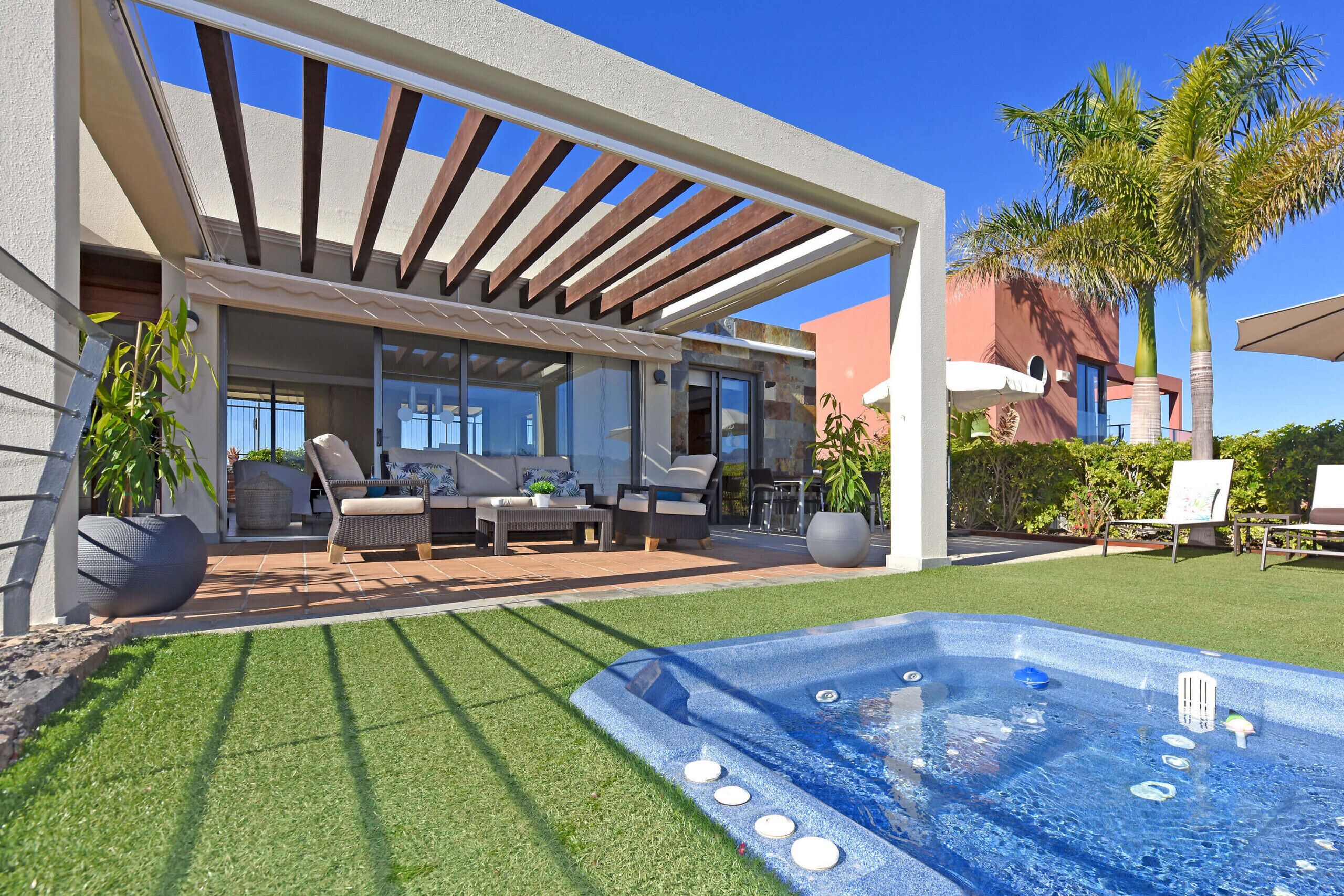 Eine moderne Außenpatio mit Whirlpool, Sitzbereich und einer Pergola.