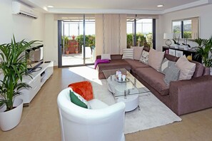 A modern living room with a sectional sofa, a glass coffee table, and potted plants. - Terrezas 2 (Maspalomas)