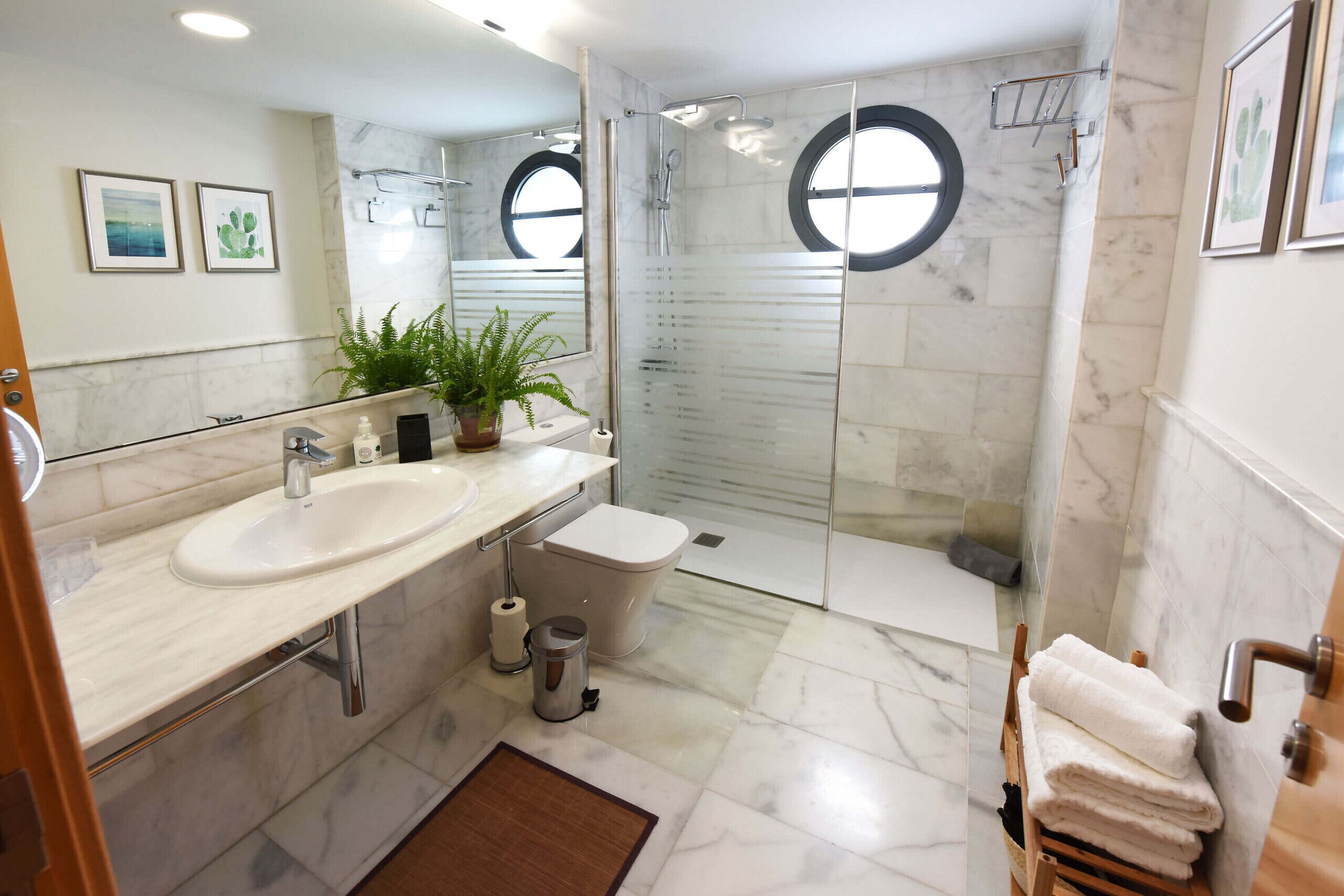 Ein modernes Badezimmer mit Marmorwaschtisch, Toilette und einer Duschkabine.