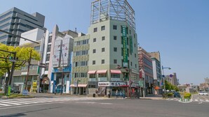 Un edificio de varios pisos con una fachada distintiva verde y blanca, que incluye un gran ventanal en el piso superior.