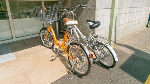 Dos bicicletas estacionadas al lado de un edificio con puerta de vidrio y pared de concreto.