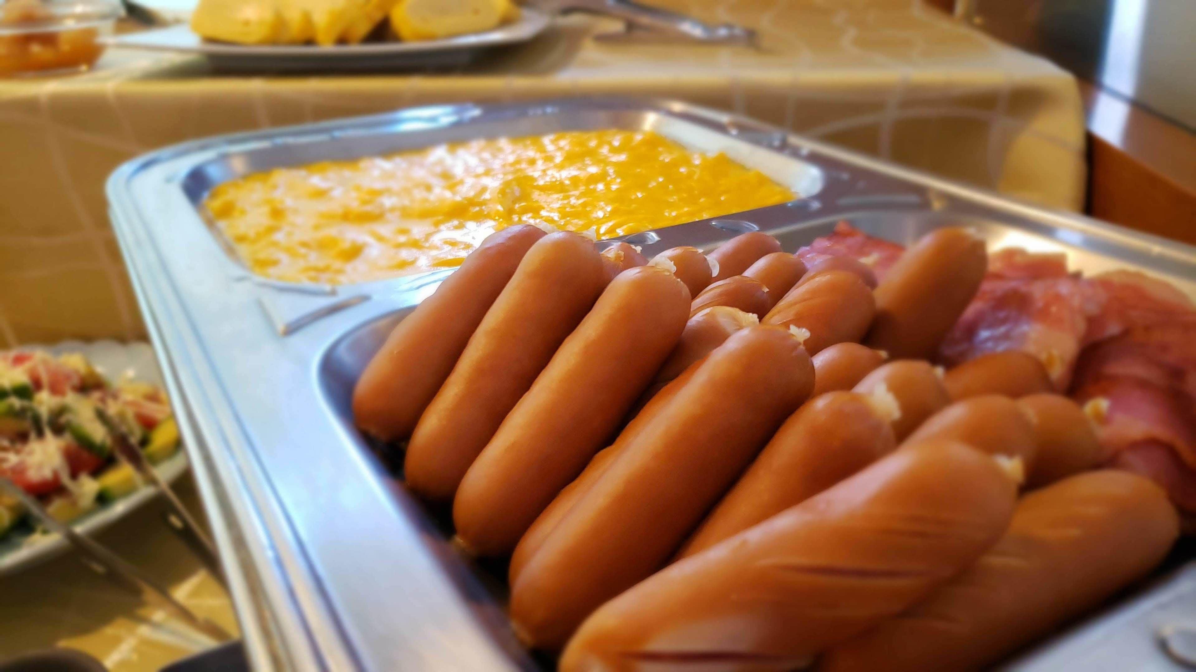 A buffet with hot dogs, cheese, and ham.
