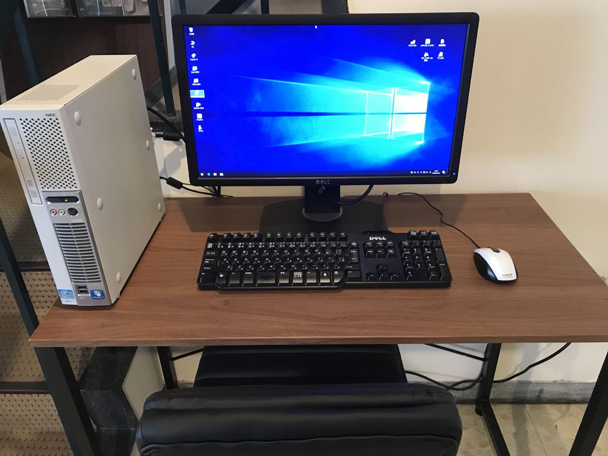 Ein Holztisch mit einem Dell-Monitor, einer Tastatur und einer Maus.