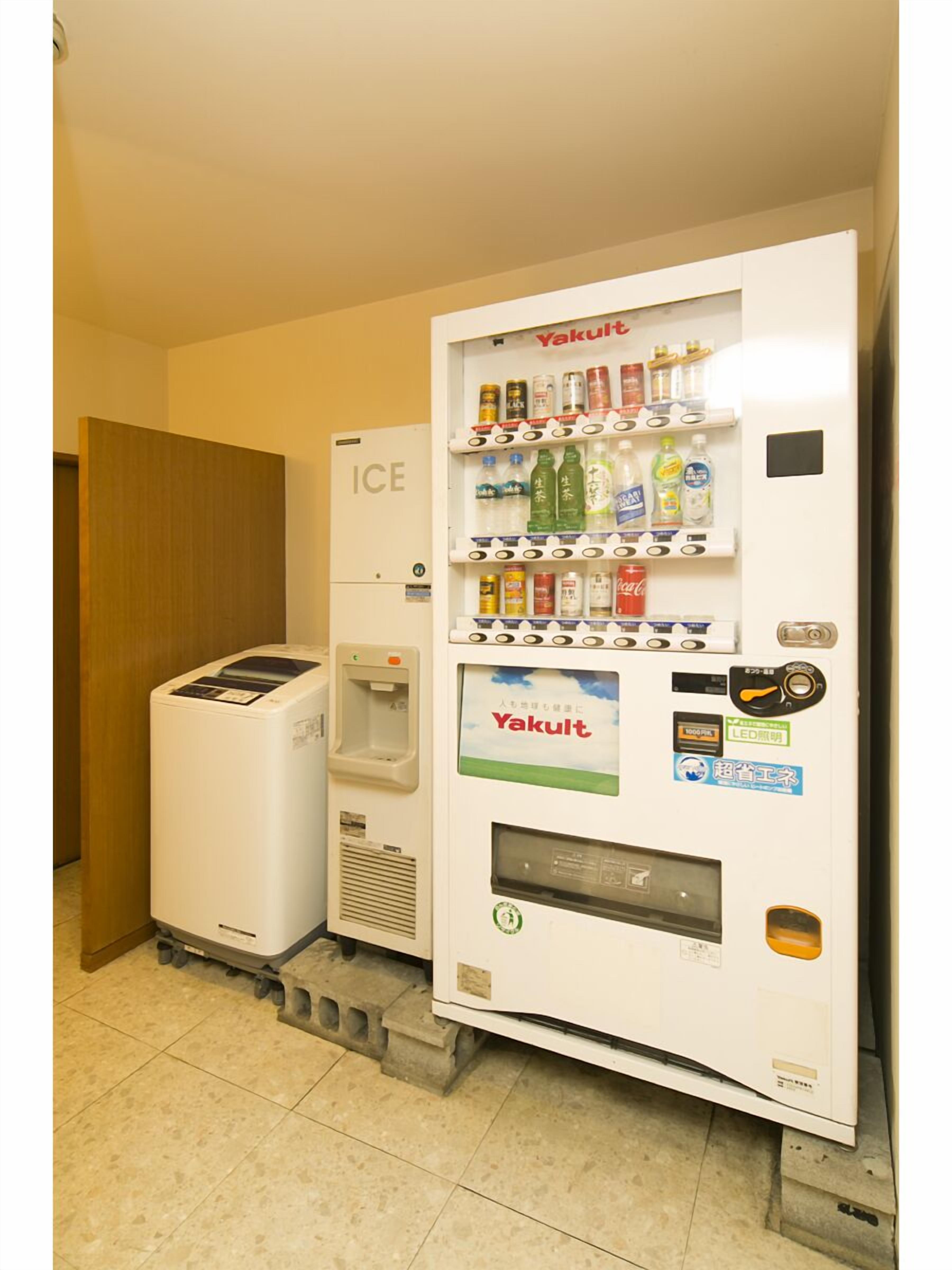 Ein Getränkeautomat mit einer Auswahl an Getränken und ein kleiner Kühlschrank mit der Aufschrift 'ICE' daneben.