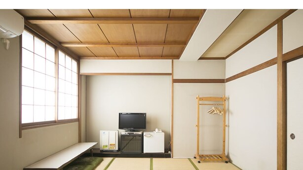 Et traditionelt japansk rum med tatamimåtter, en bænk i tatami, et fjernsyn, et lille køleskab og et træskab.