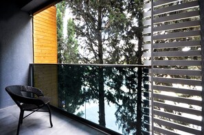 Relax on the balcony with a wicker chair and enjoy the serene view of a tall tree.