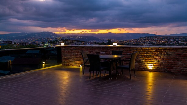 Une terrasse sur le toit, avec un mur en briques, deux tables et quatre chaises.