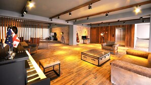 Un vaste espace de vie comprenant un piano, un grand canapé confortable, un plancher en bois et un mur en briques.