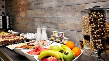 A buffet with various food items including fruits, yogurt, and cereals.