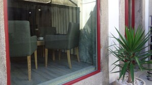 A balcony with a table and chairs, a potted plant, and a red-framed window. - Hospedaria Nossa Senhora do Carmo (Viana do Castelo)