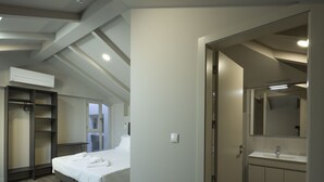 A hotel room with a bed, a walk-in closet, a bathroom with a sink and mirror, and a ceiling with recessed lighting. - Hospedaria Nossa Senhora do Carmo (Viana do Castelo)