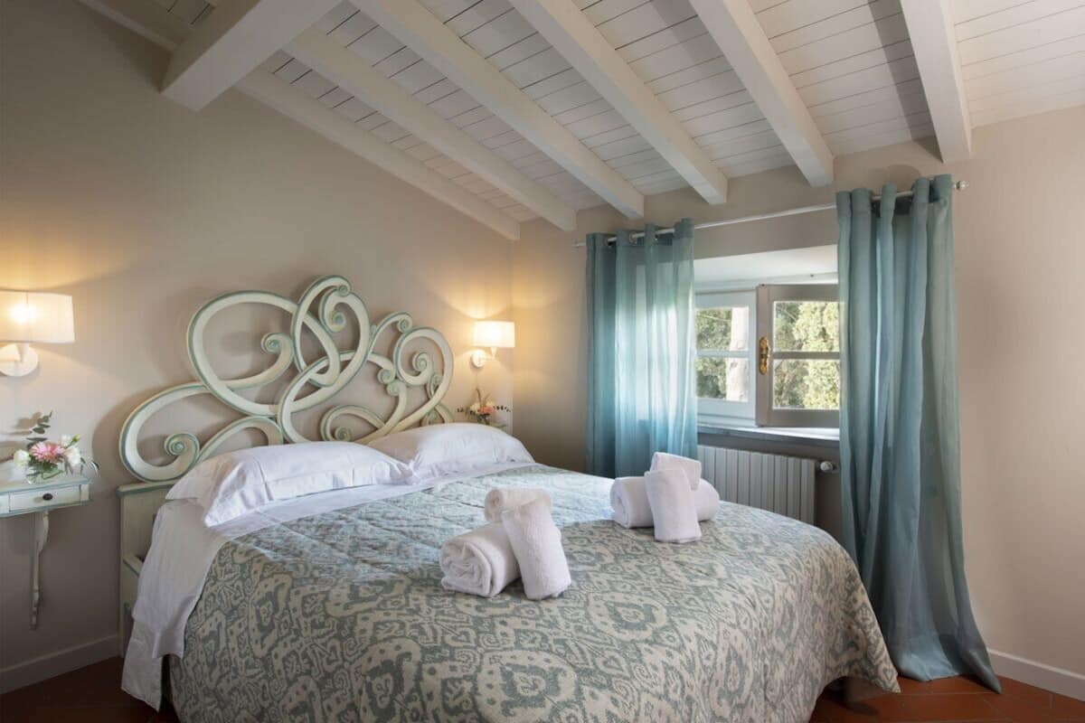Une chambre à coucher avec une couvre-lit à motifs, une tête de lit décorative, deux lampes de chevet et une fenêtre avec des rideaux.