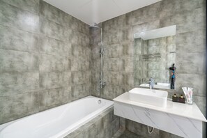 A modern bathroom with a bathtub, shower, and a vanity with a mirror. - Dandelion Apartment (Da Nang)