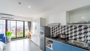 A modern kitchen with a black and white checkered backsplash, a stainless steel refrigerator, a coffee maker, and a sink. - Dandelion Apartment (Da Nang)