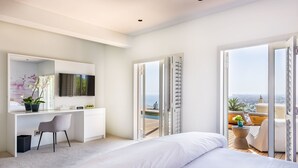 A modern hotel room with a large bed, a desk with a chair, a TV, and a balcony with a view of the city. - Kianga (Cape Town)