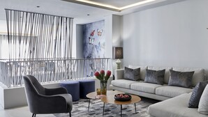 A modern living room with a grey sofa, a dark armchair, and a coffee table. There is a decorative wall with butterflies and a vase with flowers. - Kianga (Cape Town)