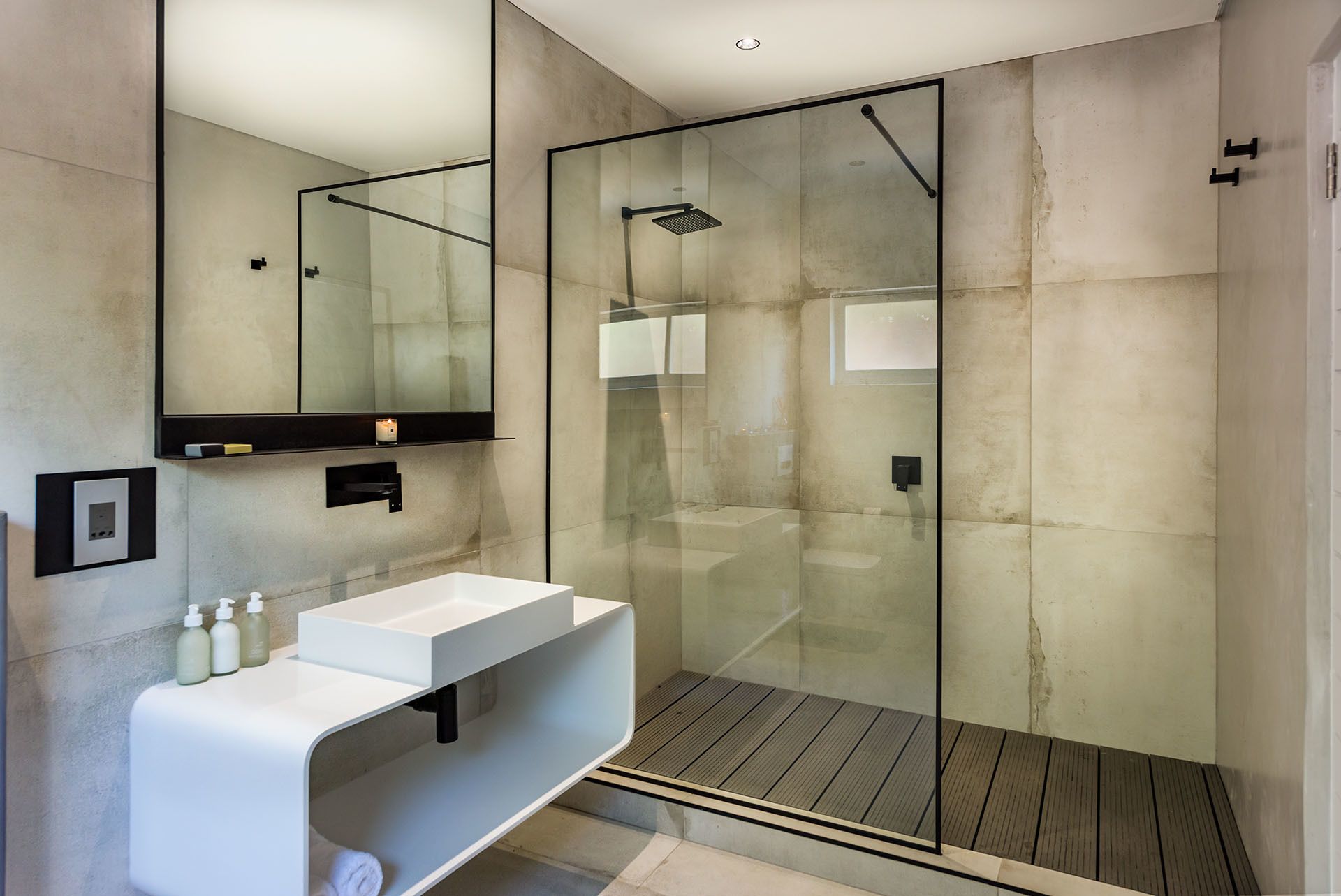 A modern bathroom with a glass-enclosed shower, a white vanity with a mirror, and a recessed ceiling light.