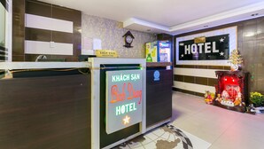 A hotel reception area with a reception desk, a clock, and a sign indicating the hotel's name. - OYO 261 Binh Dung Hotel (Ho Chi Minh City)