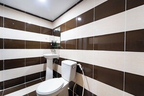 A bathroom with striped tile walls, a toilet, and a sink. - OYO 261 Binh Dung Hotel (Ho Chi Minh City)