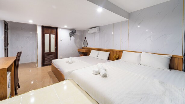 A hotel room with two beds, a wooden desk, a chair, a wooden wardrobe, and an air conditioning unit. - OYO 261 Binh Dung Hotel (Ho Chi Minh City)