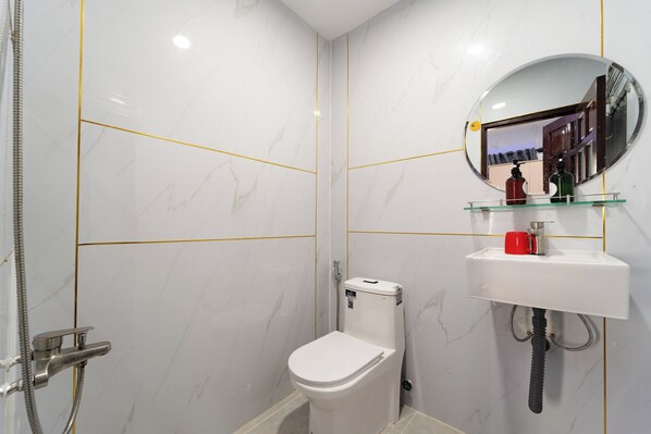 A bathroom with a toilet, a sink, and a mirror. - OYO 261 Binh Dung Hotel (Ho Chi Minh City)