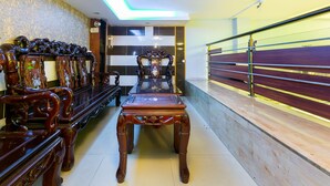 A room with a long wooden bench and chairs, a marble wall, and a staircase with a railing. - OYO 261 Binh Dung Hotel (Ho Chi Minh City)