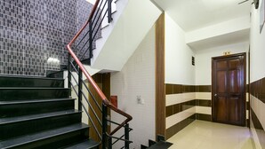 A staircase with black steps and a red handrail, leading to a landing with a wooden door marked "2-1". - OYO 261 Binh Dung Hotel (Ho Chi Minh City)