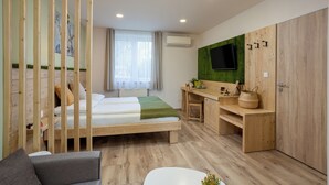 Una habitación con cama, escritorio, televisor montado en una pared verde y armario de madera.