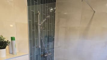 A bathroom with a toilet, a shower with a glass door, and a wooden floor.