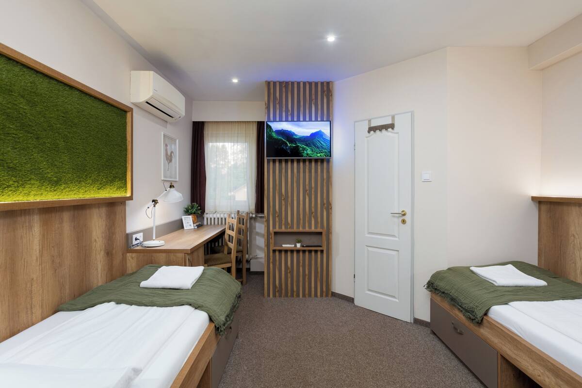 A bedroom with two beds, a desk, a chair, a TV, and a door.