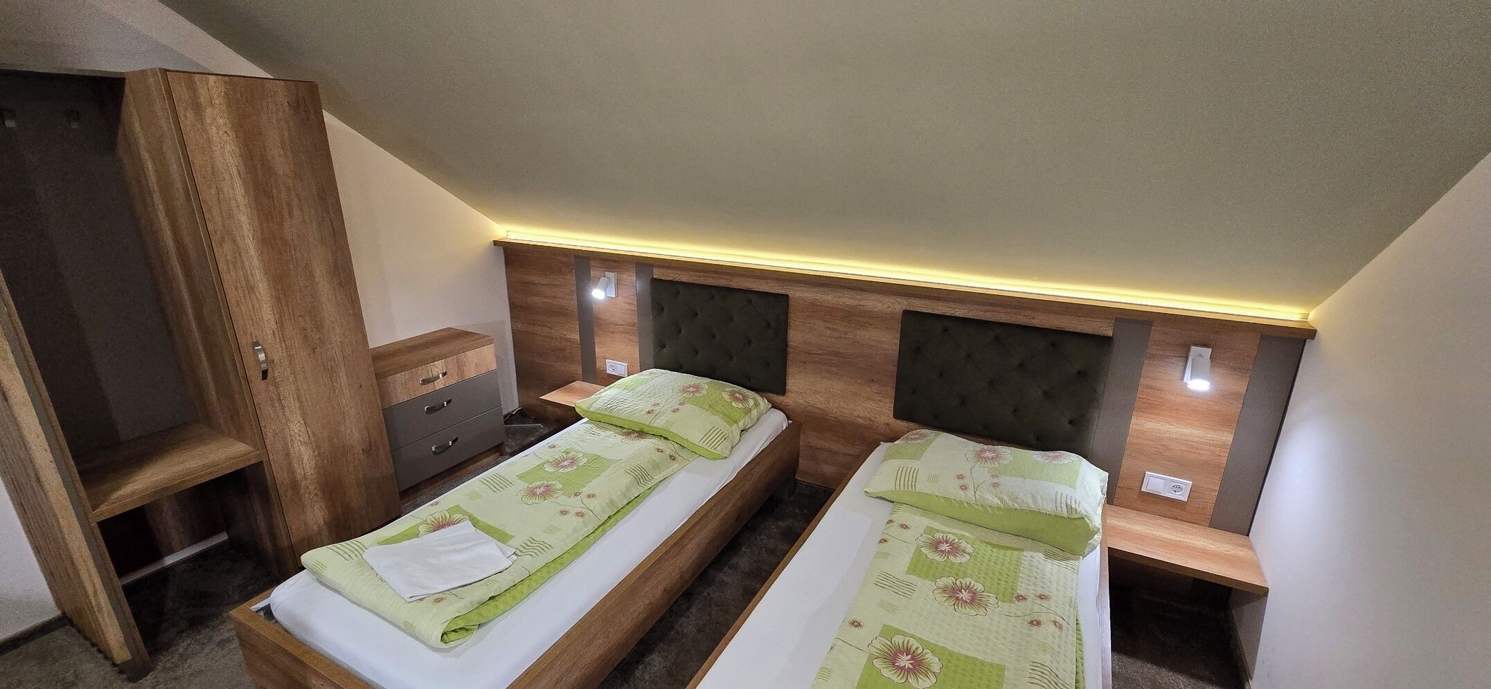 Una habitación con dos camas, un armario de madera y una mesita de noche.
