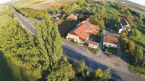 Vista aérea de una propiedad rural con una construcción grande, posiblemente una casa de campo, rodeada de campos y árboles.