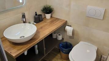 Un bagno moderno con due lavandini, un water e uno specchio con illuminazione integrata.