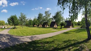 Un parque con mesas de picnic, un sendero pavimentado y un pequeño edificio.