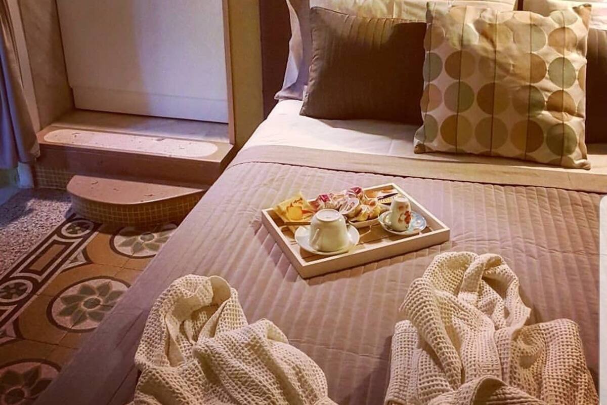 A hotel room with a bed, a tray of breakfast items, and a bathroom with a stone wall.