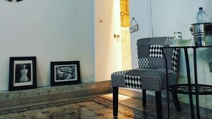 A living room with a patterned armchair, a flat-screen TV, and artwork on the walls. - Lesuite Napoli (Naples)